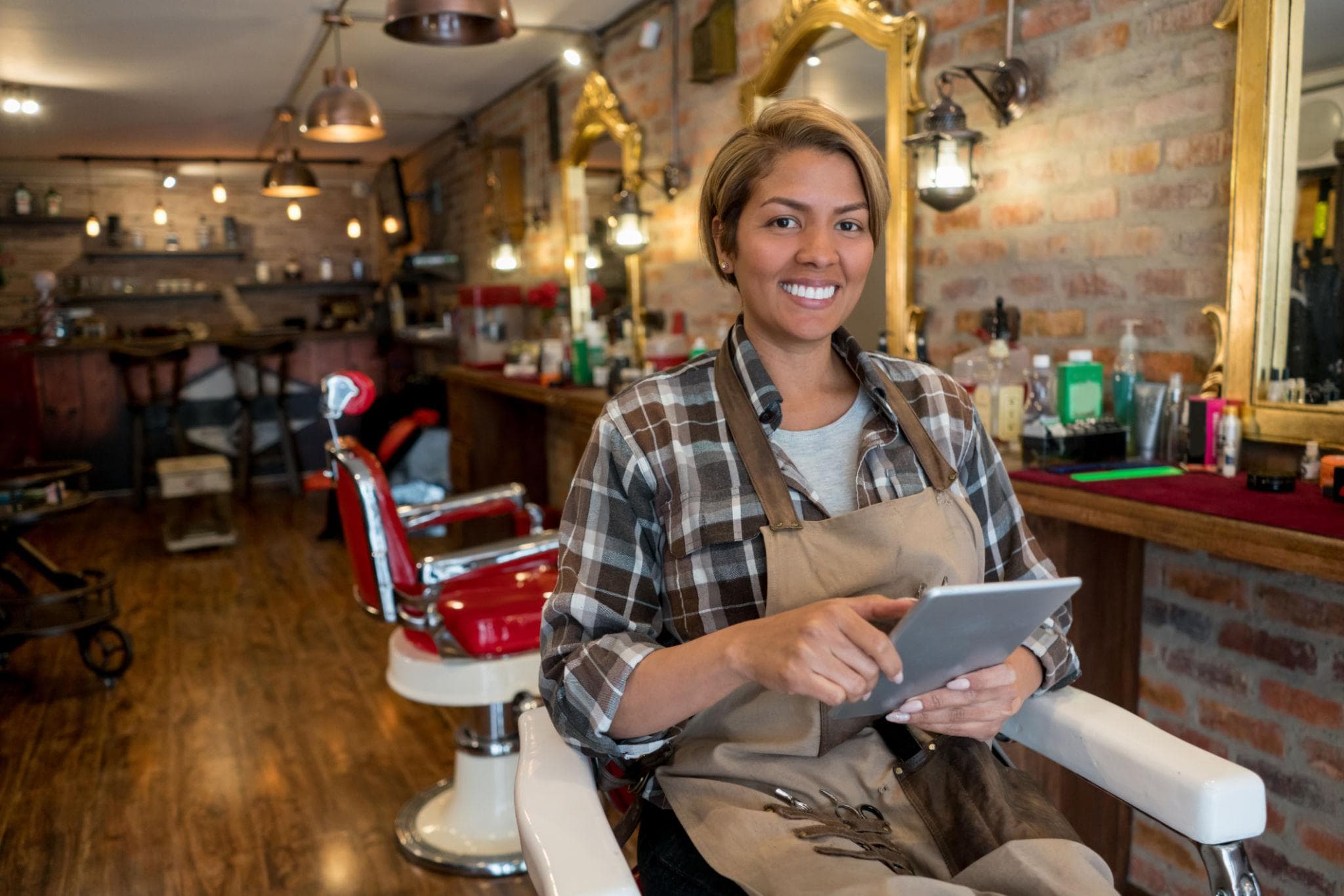 Dueña de una barbería revisando información en una tablet dentro de su local.